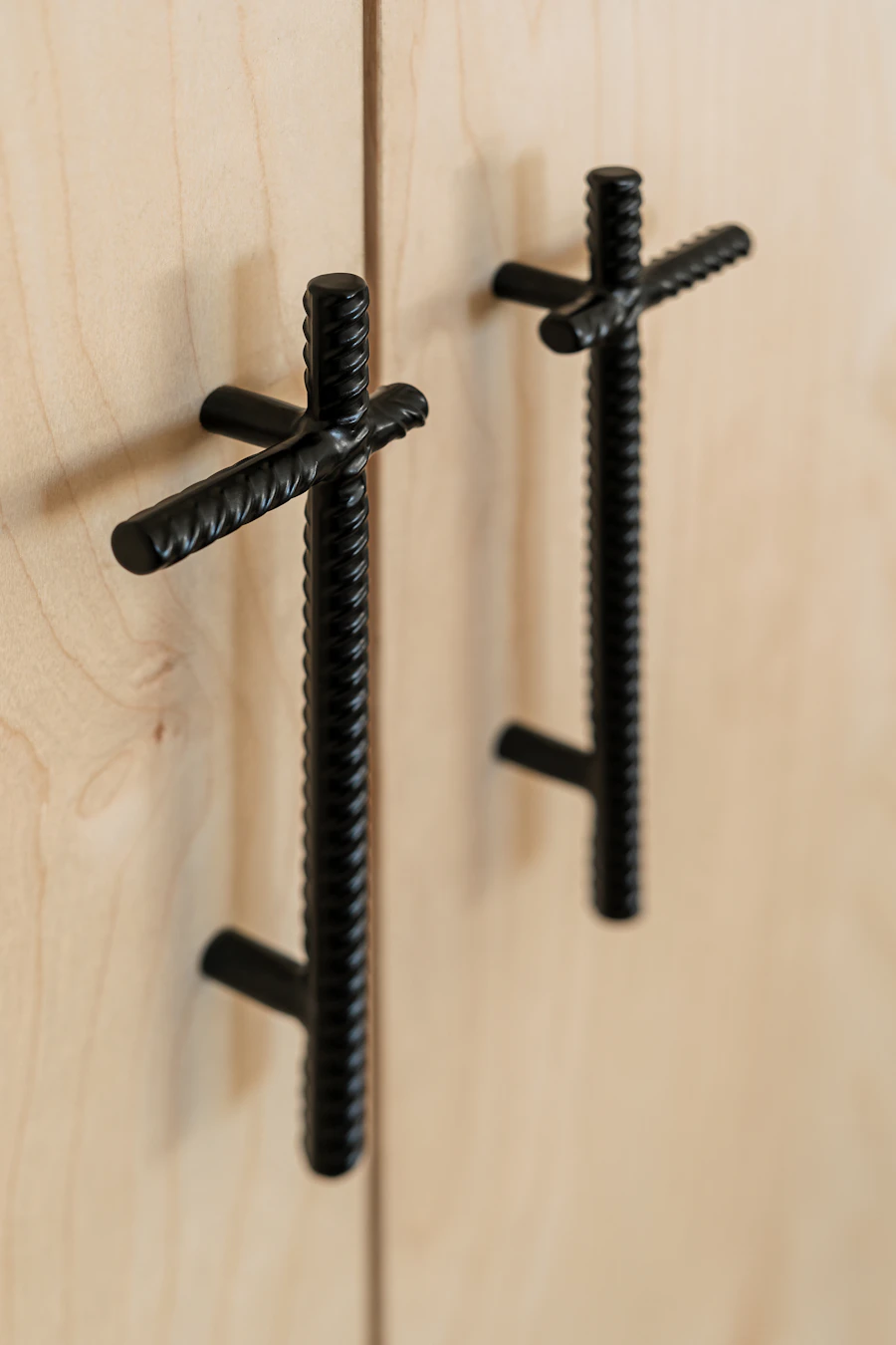 Textured black pulls on light wood cabinets