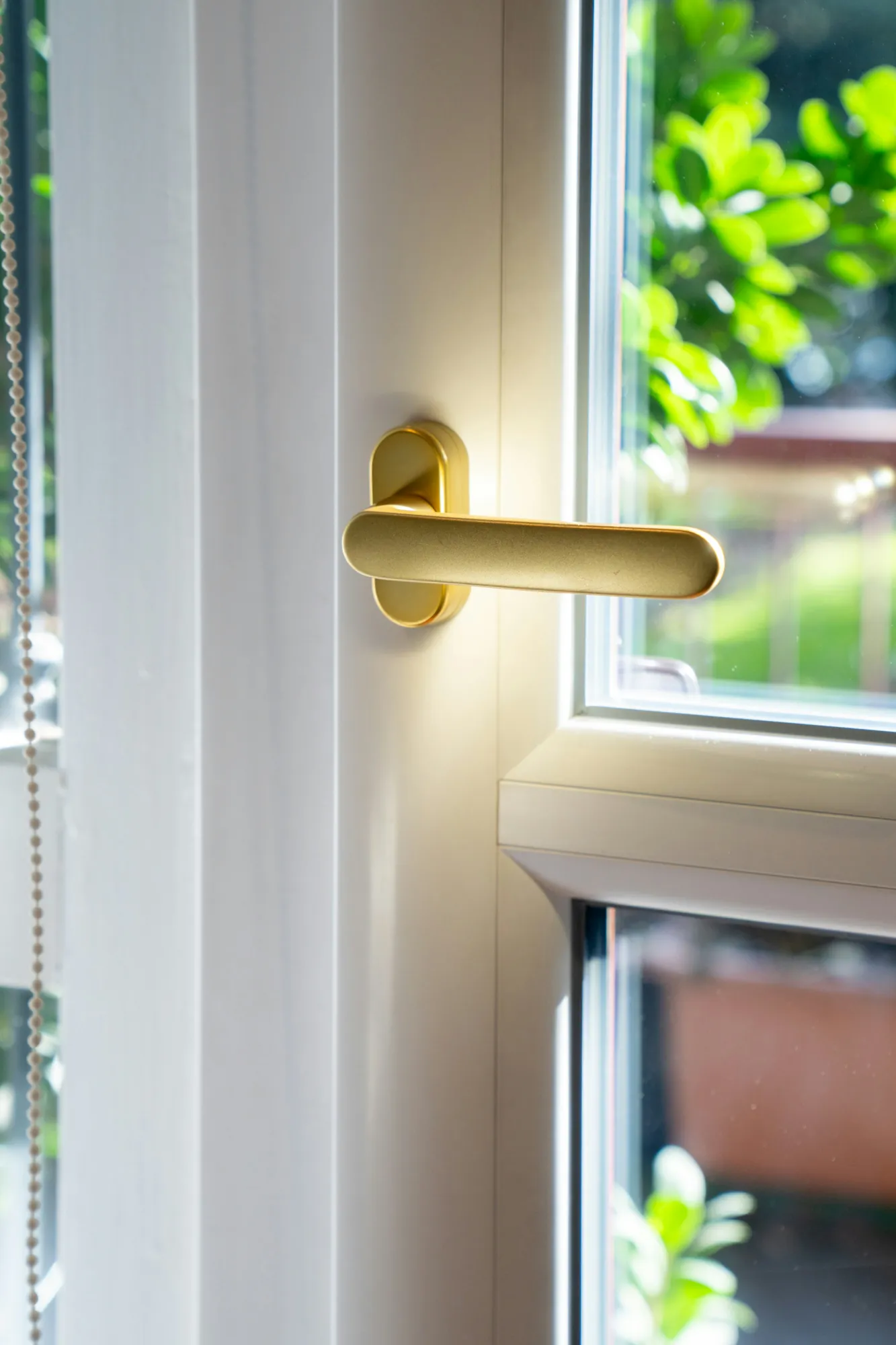 Brass lever handle on a white door by a window