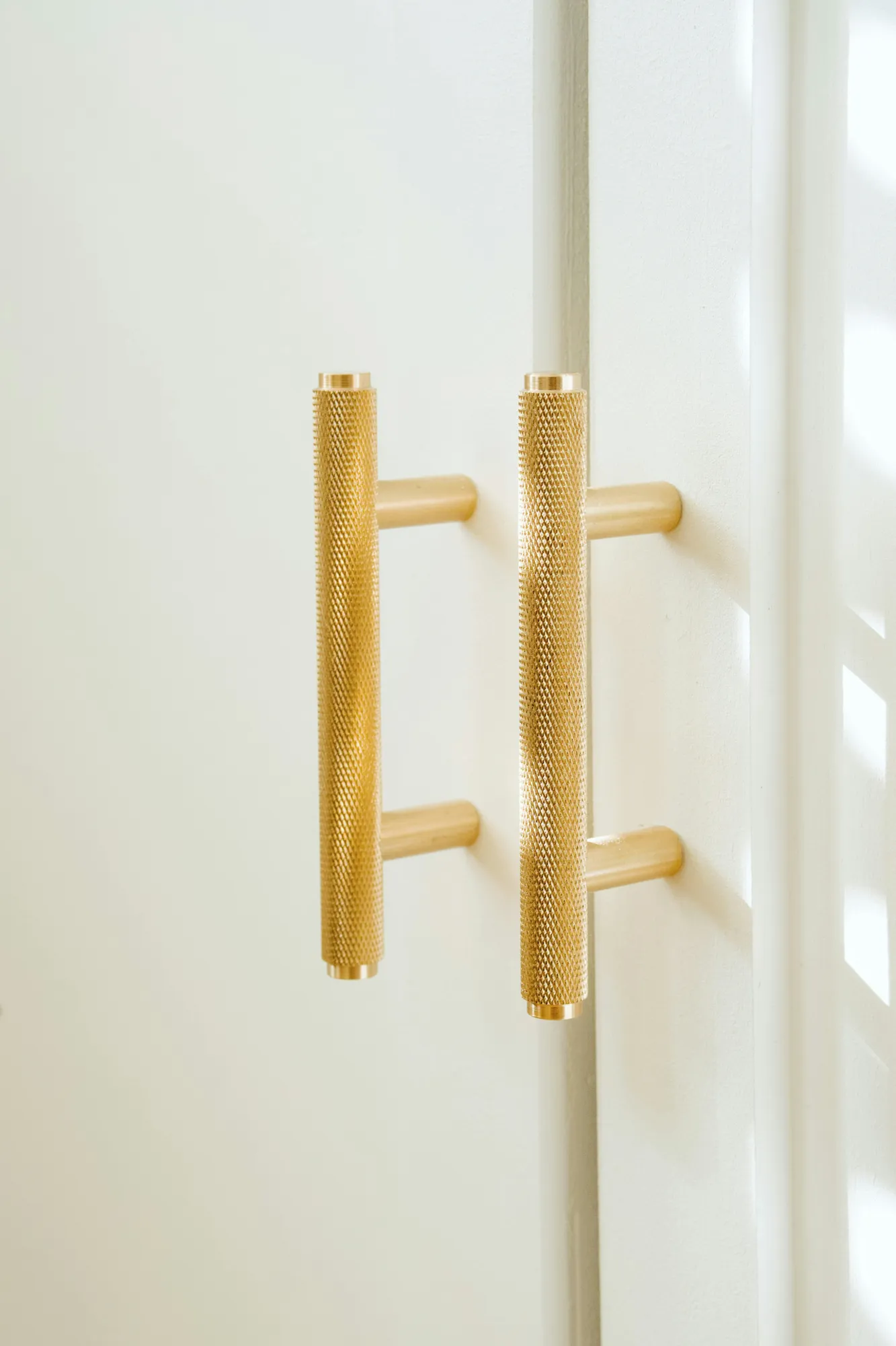 Knurled brass bar pulls on white cabinet doors